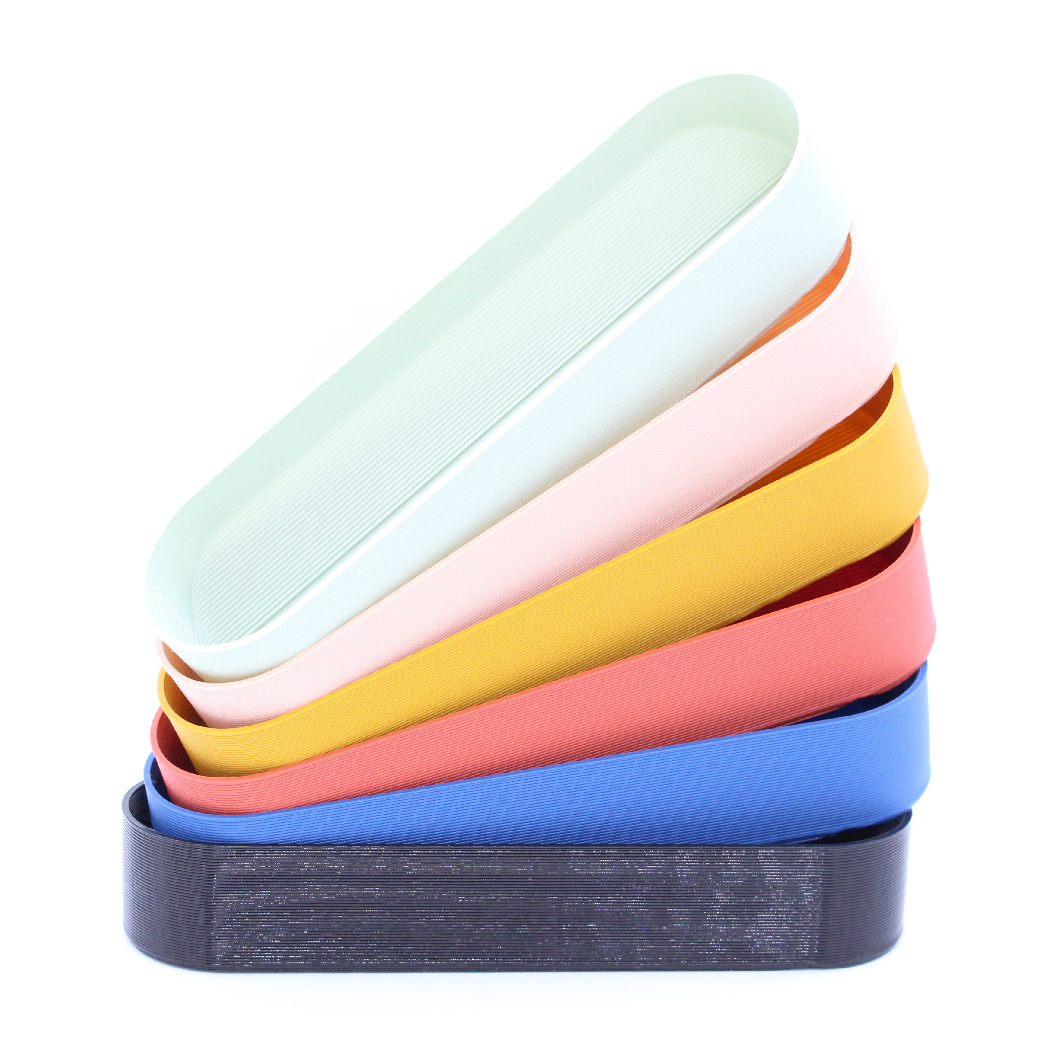 Stack of Pefto pencil trays in various colors made with recycled plastic by Deme Design